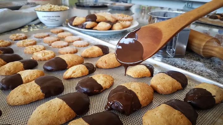 Galletas mantecadas bañadas en chocolate negro, recién hechas en el obrador