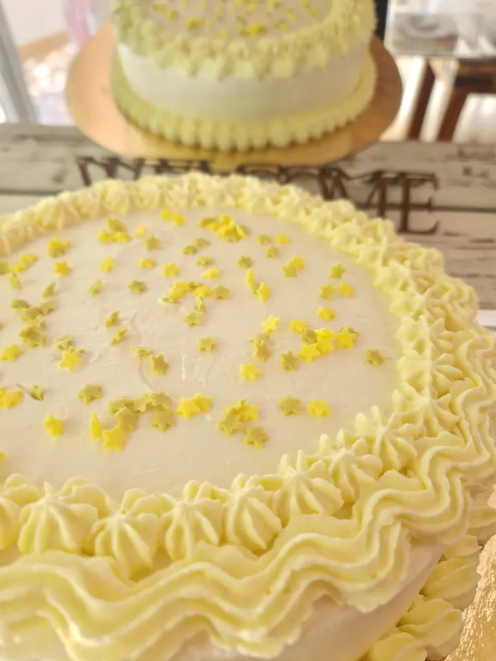 Tarta blanca decorada a mano con estrellitas amarillas y volantes de crema